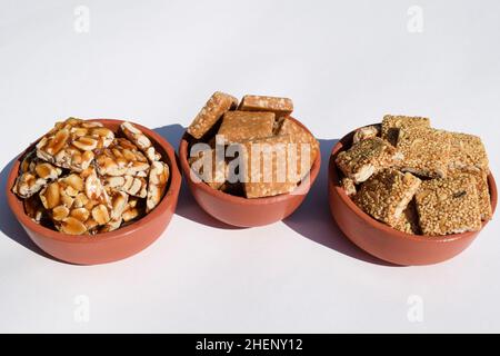 Peanut Chikki, zerkleinerte roaste Peanut Chiki, Rajgiri Chikki oder Amaranth-Sprödriegel. Jaggery mit Erdnussbonbons serviert in irdenen Schüsseln Topf während Stockfoto