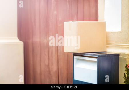 Paket im Karton auf dem Briefkasten in der Nähe des Tores Stockfoto