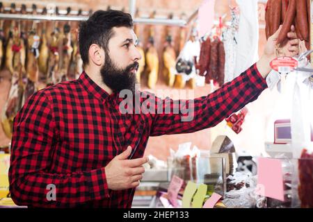 Mann, der köstliche Wurst wählt Stockfoto