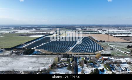 An einem klaren, sonnigen Winternachmittag in Kanada wird eine große Solarfarm am Horizont einer ländlichen Landschaft gesehen. Stockfoto