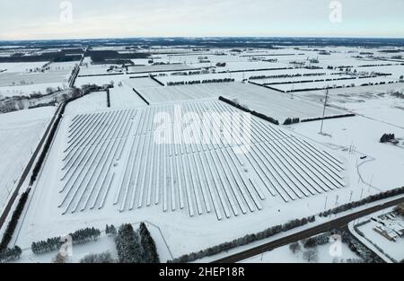 Schneebedeckte Sonnenkollektoren auf einer Solarfarm werden am Morgen eines Wintertages in der ländlichen kanadischen Gemeinde gesehen. Stockfoto