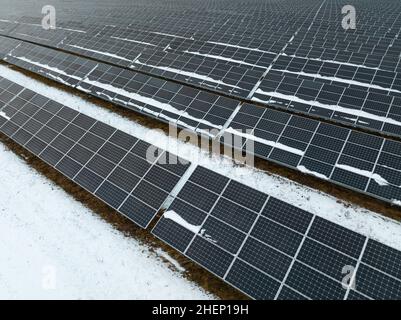 Eine hohe Nahaufnahme von Sonnenkollektoren auf einem großen Solarpark im Winter. Stockfoto