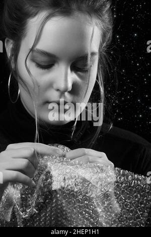 Gestresste Frau in Depression platzt Blasen der Verpackung Cellophan monochrom Stockfoto