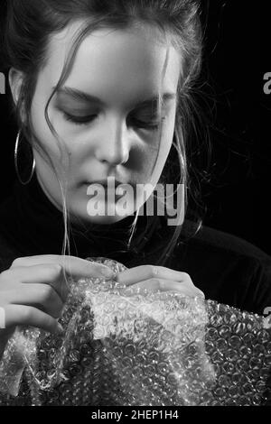 Gestresste Frau in Depression platzt Blasen der Verpackung Cellophan monochrom Stockfoto