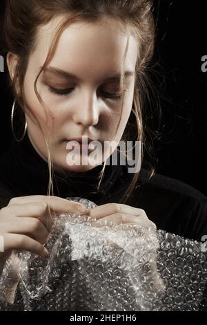 Gestresste Frau in Depression platzt Blasen der Verpackung Cellophan Stockfoto