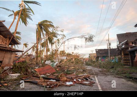 Siargao Insel am Tag nach dem zerstörerischen Taifun Odette, zerbrochene Häuser, umgestürzte Kokosnusspalmen, traurige Menschen, Sonnenaufgang und Straßen voller Müll Stockfoto