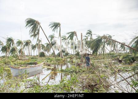 Siargao Insel am Tag nach dem zerstörerischen Taifun Odette, zerbrochene Häuser, umgestürzte Kokosnusspalmen, traurige Menschen, Sonnenaufgang und Straßen voller Müll Stockfoto