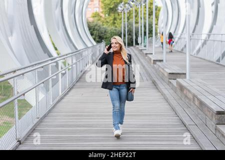 Geschäftsfrau, die auf der Straße einer Stadt mit dem Handy spricht Stockfoto