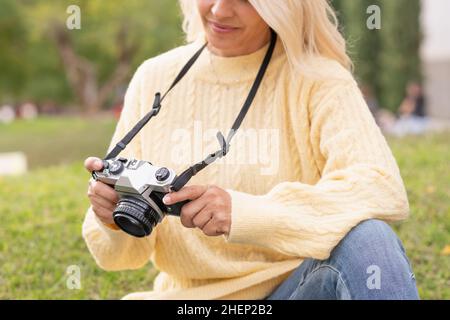 Nahaufnahme einer Frau, die eine spiegellose Digitalkamera im Freien in der Natur hält Stockfoto
