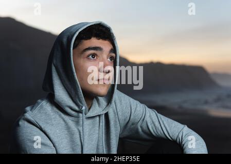 Porträt eines nachdenklichen Jugendlichen, der bei Sonnenuntergang einen Pullover trägt. Stockfoto