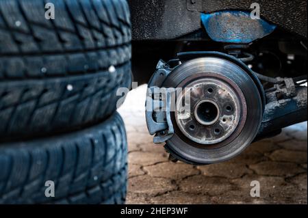 Winterreifen neben dem Auto, saisonales Reifenwechselkonzept, selektiver Fokus, Fokus auf das Auto, Nahaufnahme Stockfoto