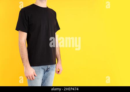 Mann in leerem schwarzen T-Shirt auf gelbem Hintergrund Stockfoto