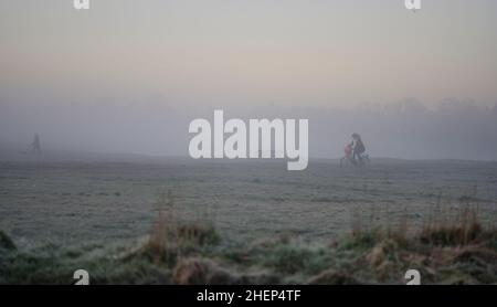 Wimbledon, London, Großbritannien. 12. Januar 2022. Menschen, die pendeln und sich fit halten, werden im Morgennebel auf dem Wimbledon Common in den Vororten im Südwesten Londons im Morgengrauen beobachtet. Quelle: Malcolm Park/Alamy Live News. Stockfoto