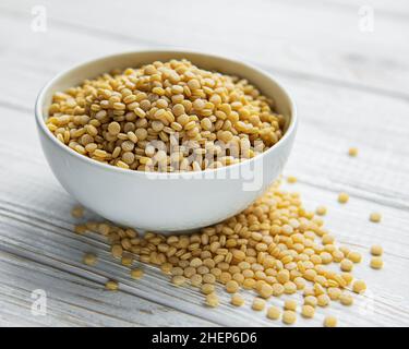 Roh Couscous in einer weißen Schüssel und Löffel auf dem Tisch Stockfoto