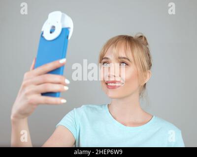 Stilvolle schöne blonde Frau Bloggerin macht Selfie mit ihrem Smartphone. Trend, Technologie, Schönheit, Modekonzept Stockfoto