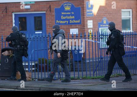 Bewaffnete Polizeibeamte vor der Earlsdon Primary School, Coventry, die geschlossen bleibt, während die Polizei mit einem Mann auf einem nahegelegenen Grundstück in der Earlsdon Avenue North in einem Stand-off bleibt. Beamte der Polizei von West Midlands wurden am Sonntag zu dem Grundstück gerufen, um eine Sozialkontrolle an einem Mann und einem Kind durchzuführen, von denen angenommen wird, dass beide noch im Besitz sind. Bilddatum: Mittwoch, 12. Januar 2022. Stockfoto