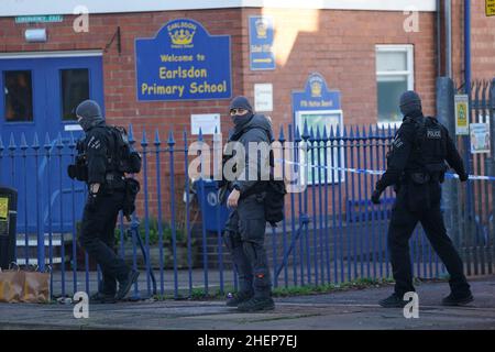 Bewaffnete Polizeibeamte vor der Earlsdon Primary School, Coventry, die geschlossen bleibt, während die Polizei mit einem Mann auf einem nahegelegenen Grundstück in der Earlsdon Avenue North in einem Stand-off bleibt. Beamte der Polizei von West Midlands wurden am Sonntag zu dem Grundstück gerufen, um eine Sozialkontrolle an einem Mann und einem Kind durchzuführen, von denen angenommen wird, dass beide noch im Besitz sind. Bilddatum: Mittwoch, 12. Januar 2022. Stockfoto