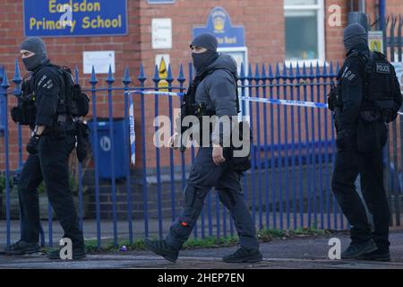 Bewaffnete Polizeibeamte vor der Earlsdon Primary School, Coventry, die geschlossen bleibt, während die Polizei mit einem Mann auf einem nahegelegenen Grundstück in der Earlsdon Avenue North in einem Stand-off bleibt. Beamte der Polizei von West Midlands wurden am Sonntag zu dem Grundstück gerufen, um eine Sozialkontrolle an einem Mann und einem Kind durchzuführen, von denen angenommen wird, dass beide noch im Besitz sind. Bilddatum: Mittwoch, 12. Januar 2022. Stockfoto