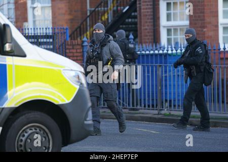 Bewaffnete Polizeibeamte vor der Earlsdon Primary School, Coventry, die geschlossen bleibt, während die Polizei mit einem Mann auf einem nahegelegenen Grundstück in der Earlsdon Avenue North in einem Stand-off bleibt. Beamte der Polizei von West Midlands wurden am Sonntag zu dem Grundstück gerufen, um eine Sozialkontrolle an einem Mann und einem Kind durchzuführen, von denen angenommen wird, dass beide noch im Besitz sind. Bilddatum: Mittwoch, 12. Januar 2022. Stockfoto