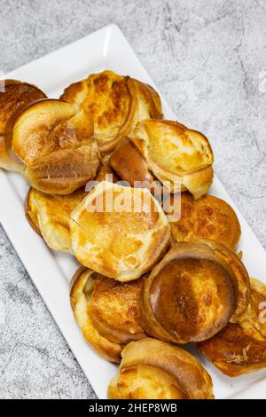 Individuelle Yorkshire Puddings auf einem weißen rechteckigen Teller. Traditionelles britisches Food-Konzept Stockfoto