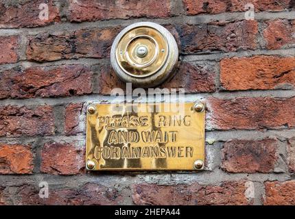 Türklingel und Informationsschild aus goldenem Metall vor einem Gebäude in Liverpool Stockfoto