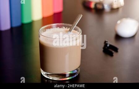 Glasbecher mit heißem Latte auf purpurpurem Schreibtisch, Kopfhörer und Bücher mit lgbt-Bewegungsfarben Stockfoto