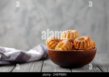 Frisch gebackene hausgemachte Muffins in einer Keramikschale auf Holzboden Stockfoto