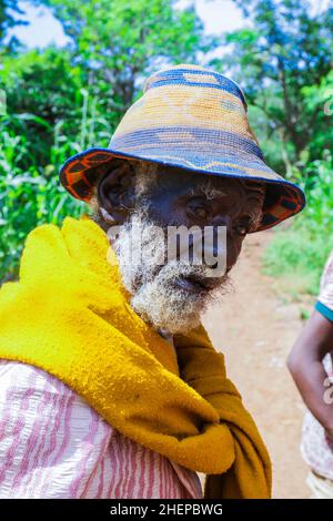 Nahaufnahme des afrikanischen Konso-Alten Mannes mit leuchtend gelben Kleidern und hübscher Mütze im lokalen Stammesdorf Stockfoto