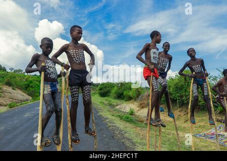 Young Boys of Benna Tribe mit traditioneller Körpermalerei auf den langen Holzstäben, die für das Bild posieren Stockfoto