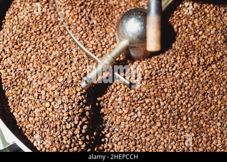 Geröstete Kaffeebohnen nach dem Rösten auf der Kühlplatte des Backofens mischen. Industrielle Bohnen rösten. Draufsicht Stockfoto