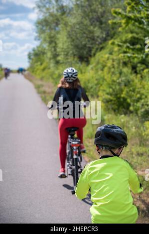 Die Familie macht eine Radtour auf einer asphaltierten Straße durch die Natur Stockfoto