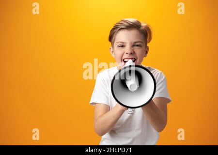 Kleiner Junge mit Megaphon auf gelbem Hintergrund Stockfoto