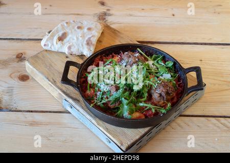 Italienische Sizzler Fleischbällchen & Gnocchi in Tomatensauce Bolognaise in einer heißen gusseisernen Pfanne serviert Stockfoto