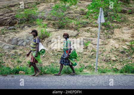 Müde Hamer Tribe Frauen kommen von Farm Work von der Grünen Landstraße zurück Stockfoto