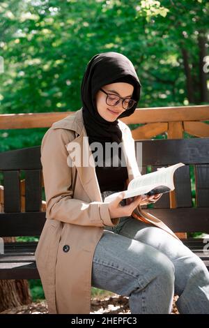 Junge muslimische Frau liest an einem schönen Frühlingstag in Stille Gedichte Stockfoto