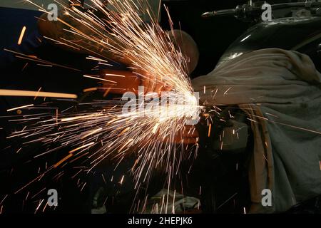 Arbeiten mit einem Winkelschleifer an einem Motorrad, sprühen Funken Stockfoto