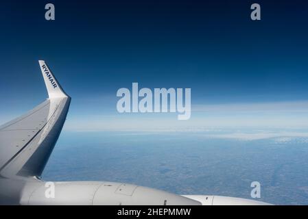 Flügelspitze einer Ryanair Boeing 737, die in großer Höhe über Frankreich fliegt, mit tiefblauem Himmel. Ryanair-Titel auf Flügelspitzen-Winglet, über Lichtwolke Stockfoto