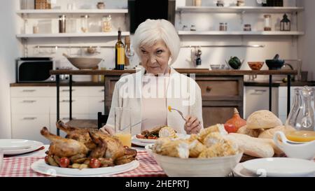 Unzufrieden Frau hält Messer und Gabel während Danksagung Abendessen in der Küche Stockfoto