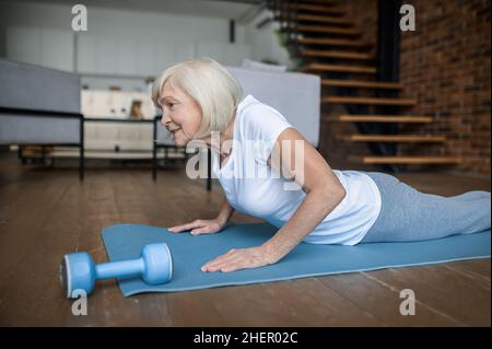 Ältere aktive Frau in einem weißen T-Shirt mit Plank Stockfoto