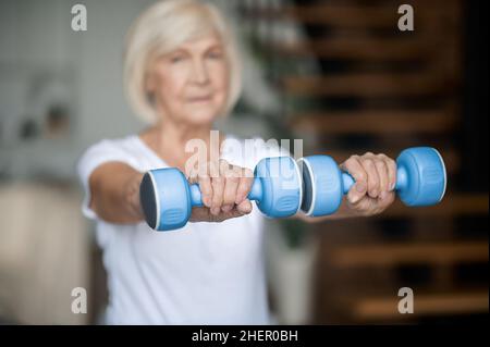 Aktive ältere Frau mit Hanteln in den Händen beim Training Stockfoto