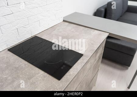 Moderne, kompakte Einbauküche mit Holzschränken, Steinplatten und eingebautem Herd und Kochfeld mit kleinen Geräten auf der Arbeitsfläche Stockfoto