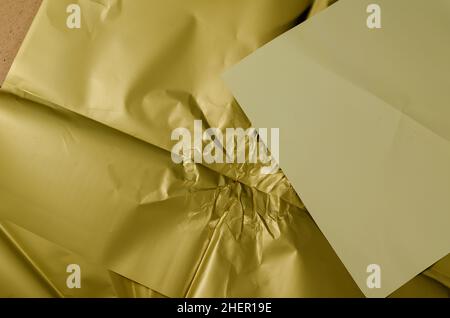 Zerknittertes olivfarbenes Geschenkpapier. Hellbeige quadratisches Blatt Papier auf der Oberseite. Unebene Oberfläche. Abstrakter Hintergrund. Selektiver Fokus. Stockfoto
