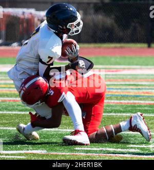 Ein High School-Fußballspieler, der den gegnerischen Spieler auf einem Rasenplatz aus der Nähe angreift. Stockfoto