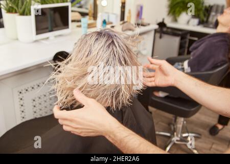 Männlicher Friseur, der junge Frau im Schönheitssalon bedient Stockfoto