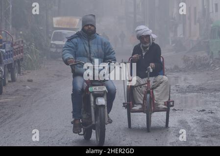 Pakistanische Bürger, Studenten auf dem Weg während eines kalten und dichten rauchigen Morgens in Lahore, Pakistan, am 11. Januar 2022. Pakistanische Bewohner und Pendler sind aufgrund der plötzlichen Schicht dichten Smogs, die Probleme bei der Atmung und der Sicht verursacht und auch den reibungslosen Verkehrsfluss behindert hat, die die Sicht der Pendler verringert und mehrere Beschwerden über Atemwegsprobleme und psychische Qualen ausgelöst hat, mehr besorgt als überrascht. (Foto von Rana Sajid Hussain / Pacific Press/Sipa USA) Stockfoto