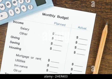 Ein Ausdruck aus einem monatlichen Budget für Ihren Text mit Bleistift und Rechner auf Holzhintergrund. Stockfoto