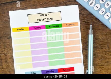 Wochenbudgetplan und Rechner mit Stift auf Holzhintergrund. Stockfoto