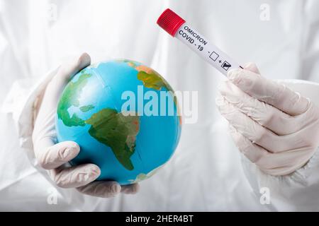 Teilansicht des Wissenschaftlers in einem Hazmat-Anzug und Latexhandschuhen mit Globus und positivem Covid-19-omicron-Variantentest, Stockbild Stockfoto