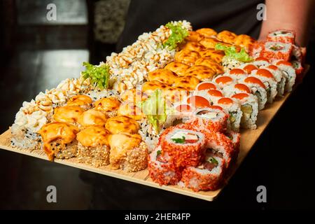 Big set of sushi rolls on a board in the hands of a waiter Stockfoto