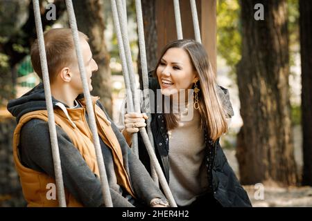 Internationales glückliches Paar im Herbst im Park im Wald auf einer Schaukel. Hochwertige Fotos Stockfoto
